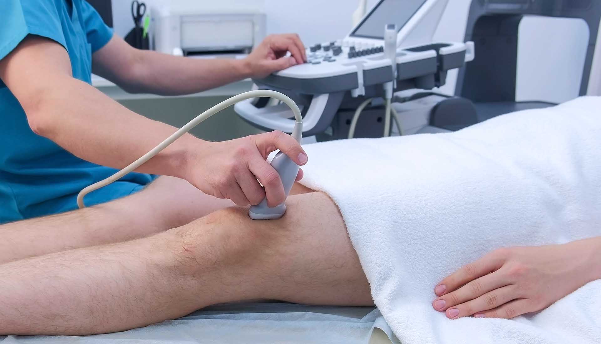 Doctor makes ultrasound of knee joint.